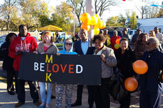 A group of people hold a sign reading "Martin Luther King Junior" and "Beloved."